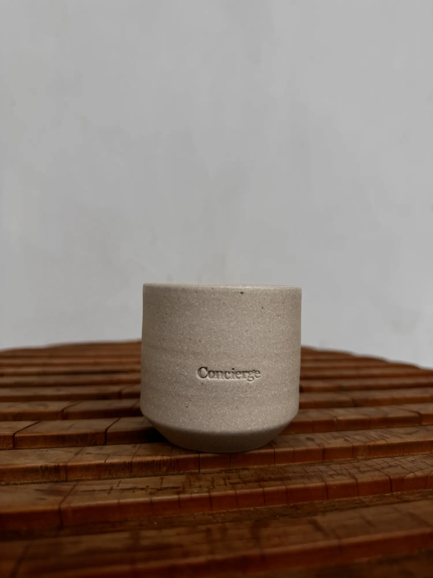 A Concierge Coffee ceramic cup on a wooden slat table