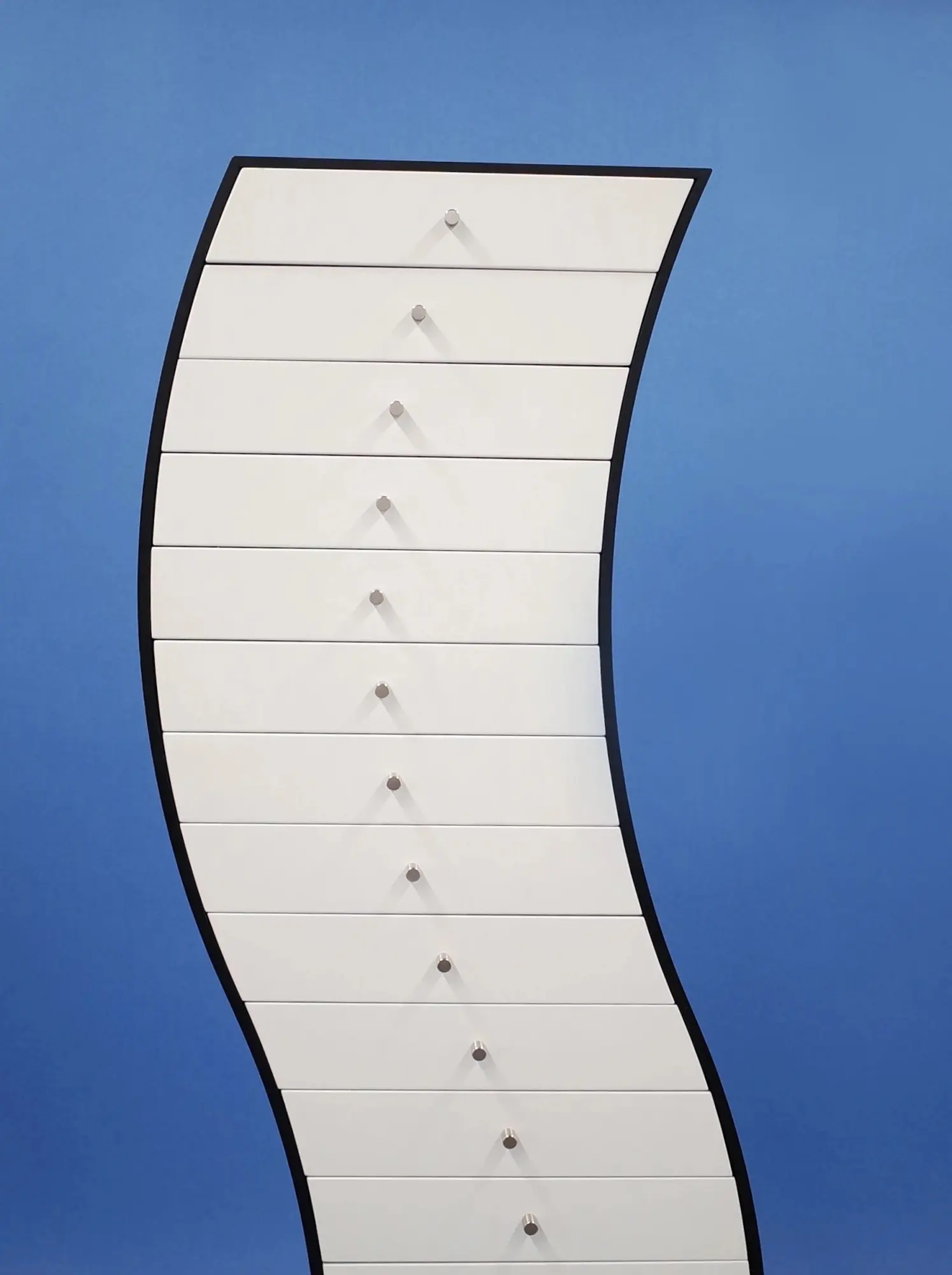 A tall curved white chest of drawers at Formas
