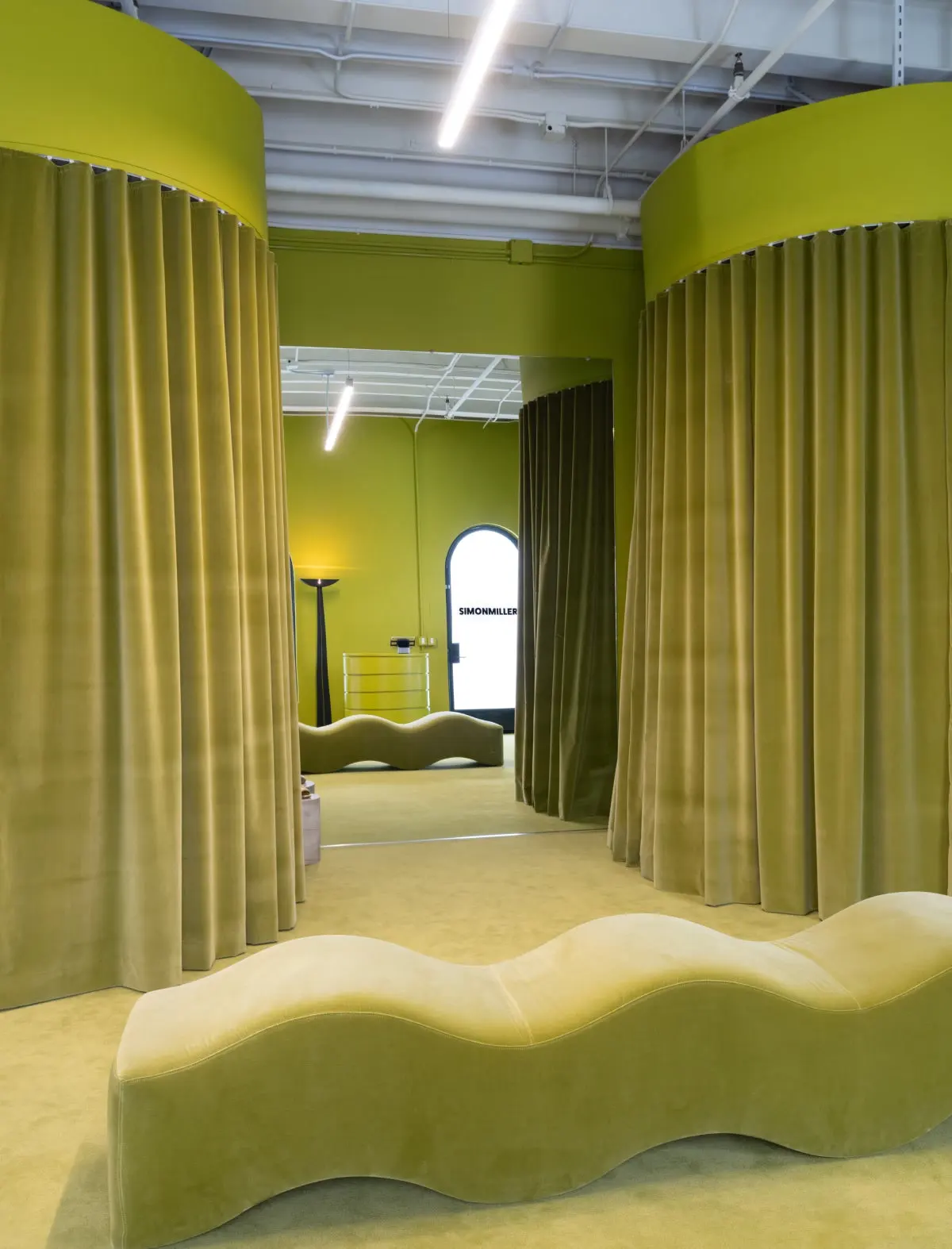 Green curtains and a wavy bench in the Simon Miller store at Signal